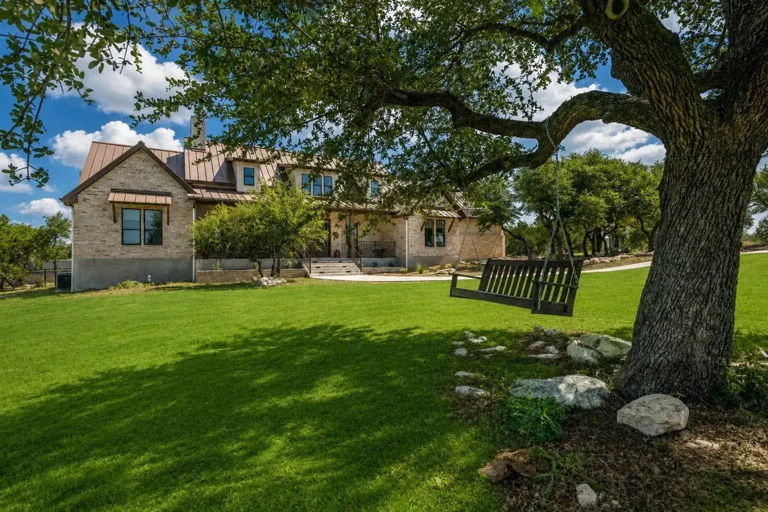 Hill Country home framed by a mature oak tree and swing
